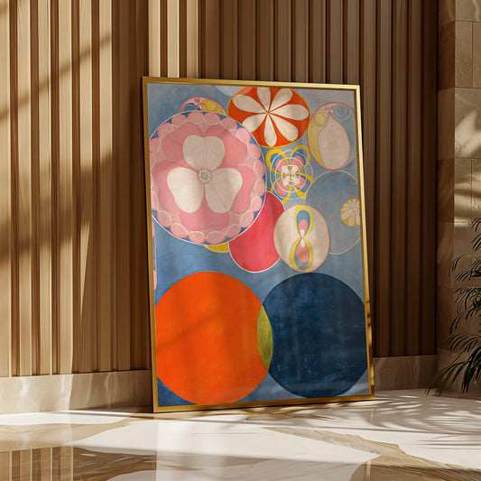 Colorful abstract art piece in a gold frame on a wooden floor with a striped wall background