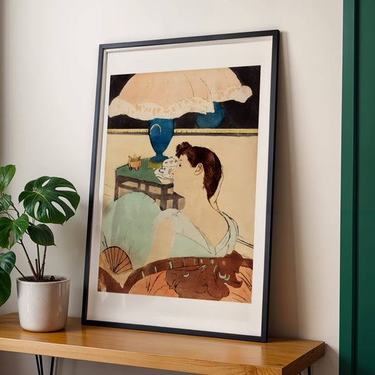 Framed artwork of a woman with an umbrella on a wooden shelf with a plant.