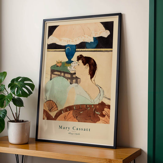 Framed artwork of a woman with an umbrella on a wooden shelf with a plant.