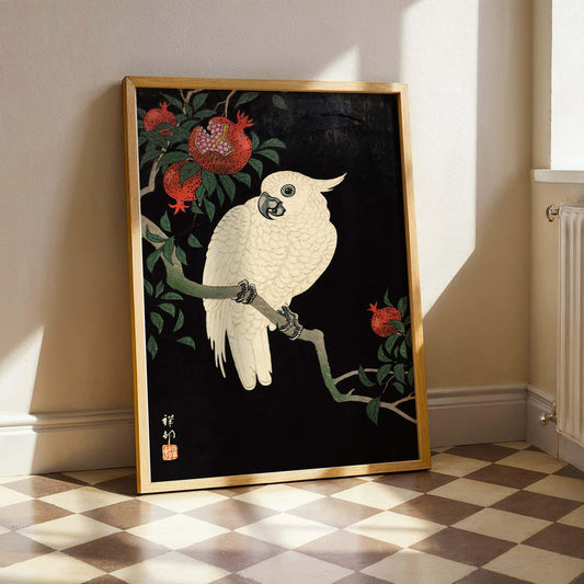 Cockatoo and Pomegranate by Ohara Koson. Framed artwork of a white bird on a branch with red flowers in a room with checkered floor.