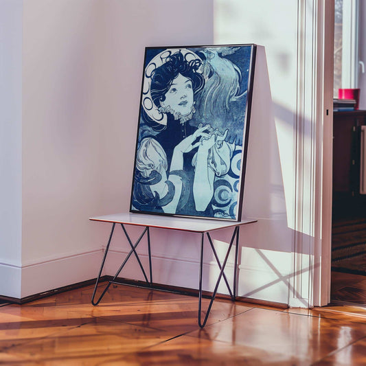 Cocorico by Alfons Mucha. Framed artwork on a stand in a room with wooden flooring and a window.