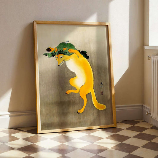 Framed artwork of a yellow creature with a green hat on a checkered floor. Dancing Fox with Lotus-Leaf Hat by Ohara Koson