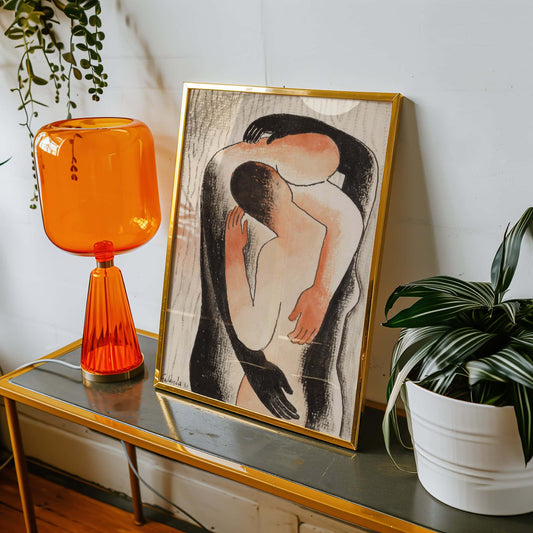 Orange table lamp and framed artwork on a console table with plants.