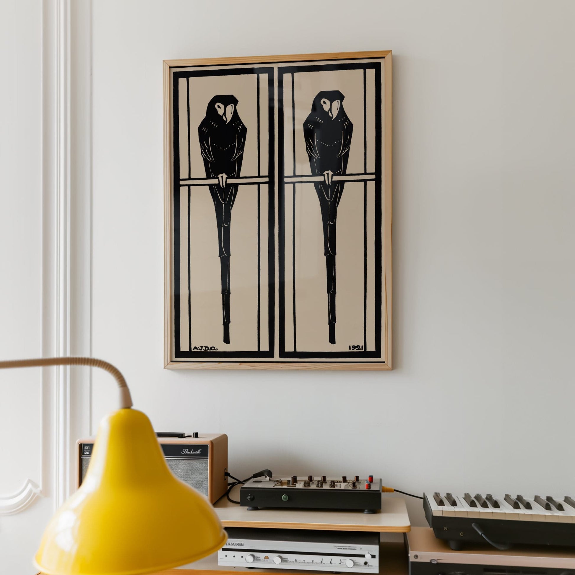 Framed artwork of two black birds on a beige background, displayed above vintage electronic equipment.