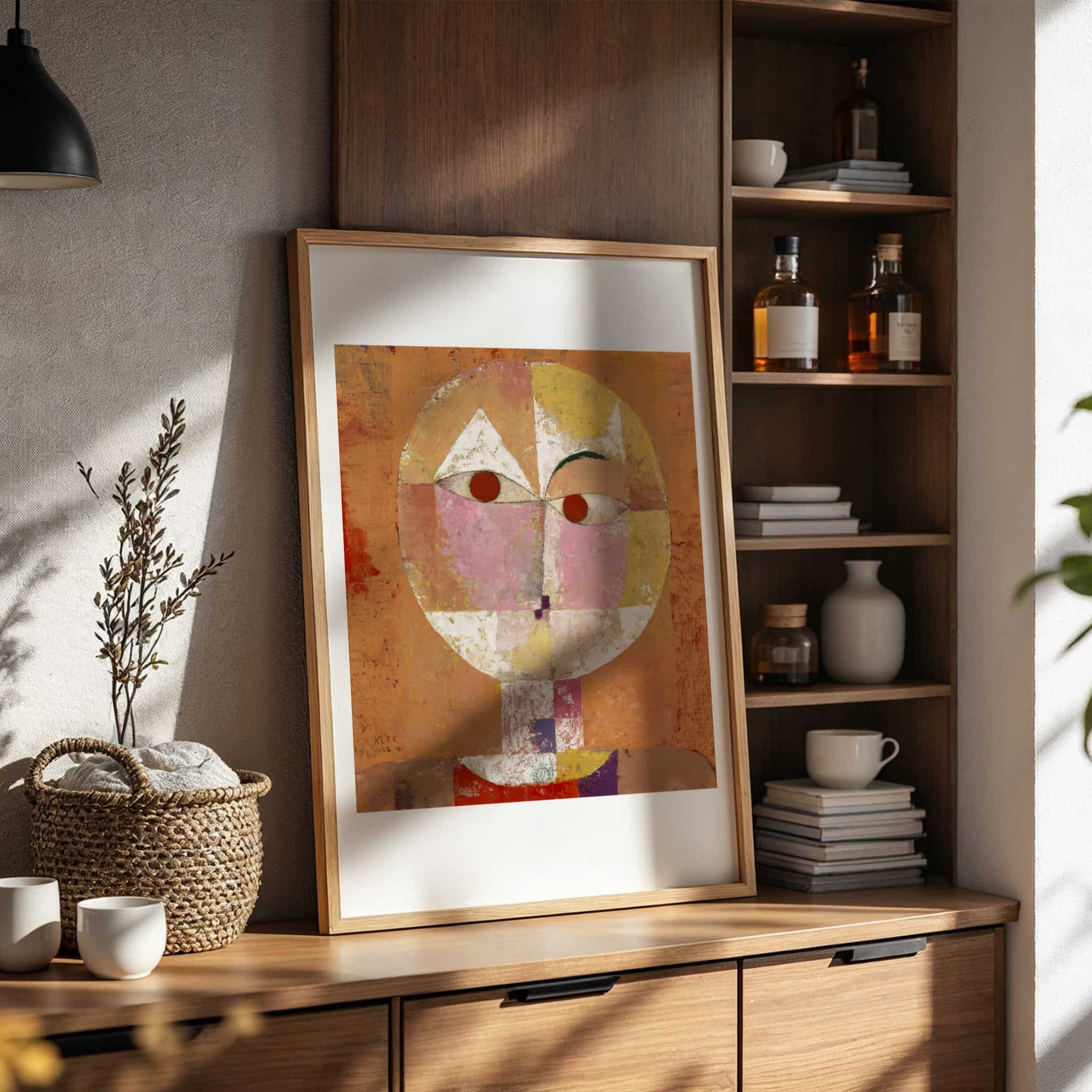 Senecio by Paul Klee. Framed abstract art piece on a wooden shelf with books and bottles.